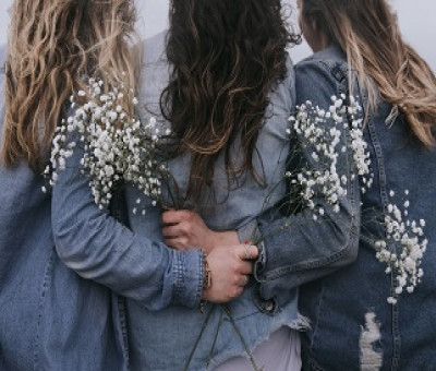 foto de mujeres de espaldas abrazándose, con flores en sus manos
