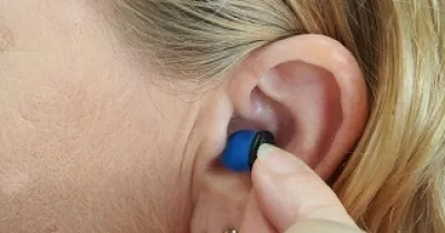 Mujer poniéndose un audífono por pérdida auditiva