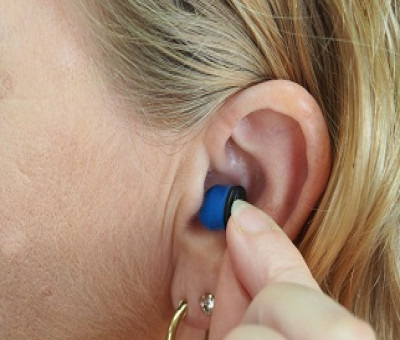 Mujer poniéndose un audífono por pérdida auditiva