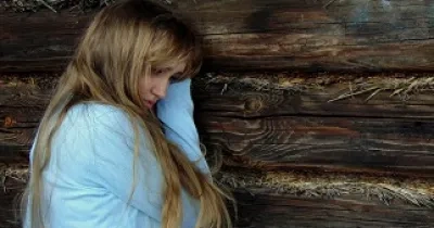 chica joven triste apoyada en la pared