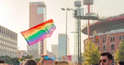Bandera del movimiento LGTBI+ ondeando sobre multitud de personas