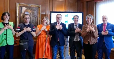 Voluntarios de la ONCE hacen el signo del voluntariado, cruzando las mano sobre el pecho