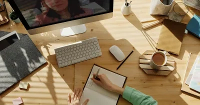 Persona tomando notas delante de un PC