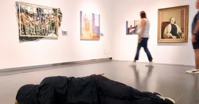 Sala de exposición en donde hay cuadros colgados y una pieza escultórica en el suelo