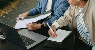 Estudiantes delante de un portátil tomando notas