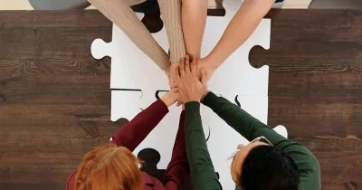 Grupo de personas con la manos unidas unas sobre las otras