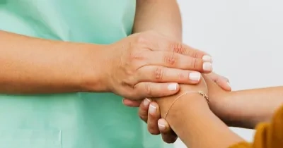 Manos de cuidadora cogiendo manos de una paciente