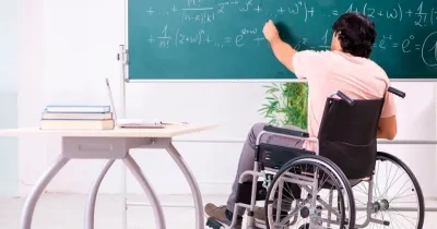 Un profesor con discapacidad en silla de ruedas escribe en una pizarra | Foto de 123RF/Elnur