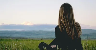 Mujer sentada en el suelo mirando al horizonte
