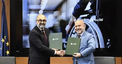 Los dos representantes firmando el acuerdo mientras se dan la mano 
