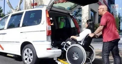 Un taxista ayuda a entrar en su vehículo a una cliente en silla de ruedas | Foto del Ayuntamiento de Madrid
