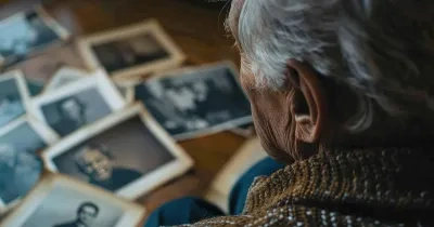 Un hombre mayor observa fotografías familiares sobre su mesa