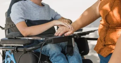 Persona en silla de ruedas junto a cuidadora 