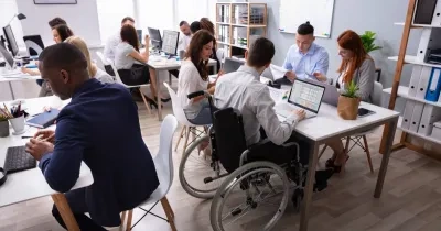 Un técnico en silla de ruedas comparte espacio de trabajo en una oficina colaborativa 