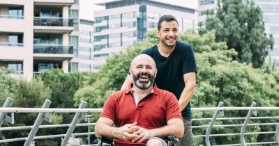 Imagen de un hombre en silla de ruedas acompañado durante un paseo