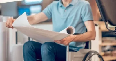 Un hombre en silla de ruedas con unos documentos en la mano