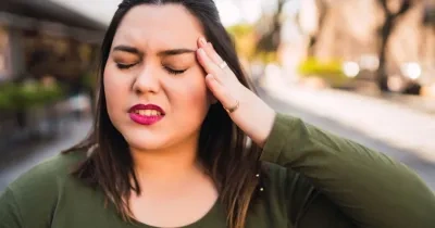 Una mujer se toca la cabeza por una migraña