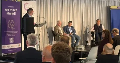 Los ponentes subidos en el escenario del evento, con un moderador en el atril y a su espalda el cartel de AccesibleEU