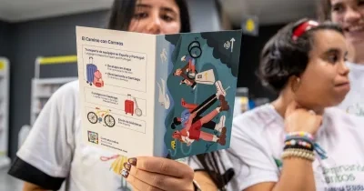 Participantes en una actividad del proyecto Camino + Accesible sostienen un folleto informativo de El Camino con Correos, que recoge servicios para peregrinos como el transporte de equipajes, el envío de bicicletas y la consigna en Santiago de Compostela.