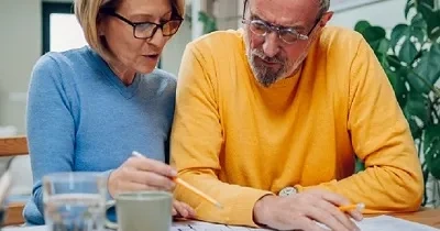 Dos personas mayores con riesgo de padecer algunas de las patologías propuestas debido a su edad, estudiando lo que les queda para su jubilación (Fuente: COCEMFE)