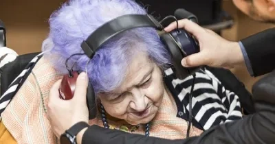 señora mayor probando su audición con unos auriculares