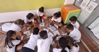 Varios alumnos en círculo mientras juegan y aprenden con pictogramas en el centro