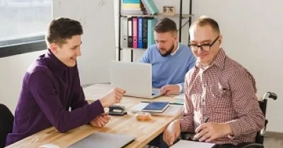 Personas trabajando juntas en su propio negocio, una de ellas con discapacidad y en silla de ruedas (Fuente: Servimedia)
