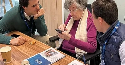 Voluntarios de Axis Corporate ayudando a una persona mayor en el Taller "Abuelos Hackers", para reducir la brecha digital (Fuente: Axis Corporate)