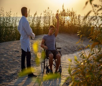 Una persona en silla de ruedas en una playa adaptada con un acompañante (Fuente: Servimedia)