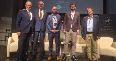 Cinco ponentes posan sobre el escenario de la Convención Europea de la Dependencia 2026, celebrada en Madrid. Detrás de ellos se observa una pantalla con el nombre del evento y varios logotipos institucionales. En el escenario hay sillones blancos y mesas auxiliares, en un espacio preparado para una mesa de debate sobre el futuro de los cuidados de larga duración, la atención sanitaria y la dependencia en Europa.