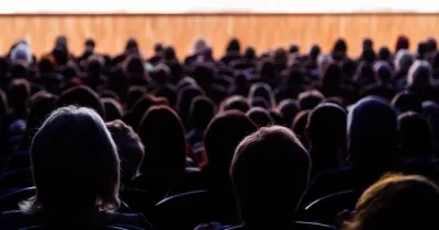 Siluetas de personas de espalda mirando una funcion teatral