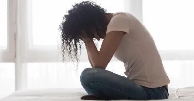 Mujer en la cama sentada con los brazos en la cara mostrando soledad o tristeza