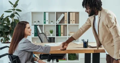 persona en silla de ruedas dando apretón de manos a un hombre con traje