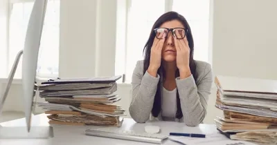 Mujer llevándose las manos a los ojos debido al agotamiento visual del trabajo