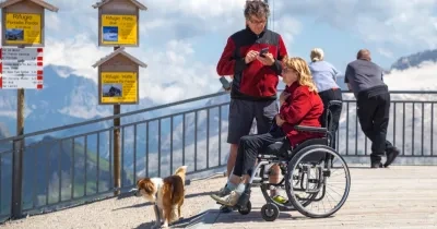 Una pareja con su perro, ella en silla de ruedas, disfrutando de un turismo en la montaña