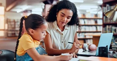 Una mujer con una niña haciendo una tarea