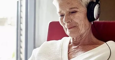 Una persona mayor escuchando por unos auriculares (Fuente: Oticon)