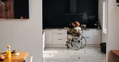 Una mujer en silla de ruedas cocinando en su casa