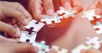 Varias manos intentando encajar un puzzle en circulo (Fuente: Servimedia)