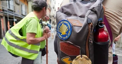 un peregrino durante el Camino de Santiago con un chaleco reflectante y una mochila