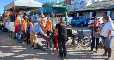 Varias personas voluntarias subiendo a una usuaria en silla de ruedas a un autobús turístico.