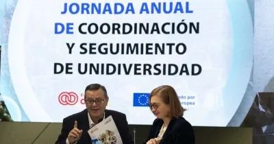 Los representantes de las dos entidades haciendo un acto delante de una pantalla digital donde pone el nombre de la jornada