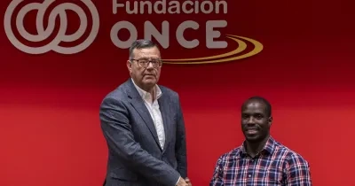 Amadou y Donoso estechándose la mano delante del logo de Fundación ONCE