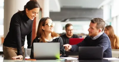 Tres personas hablando delante de la pantalla de un ordenador en la oficina