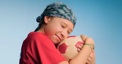 Niño con cáncer infantil jugando con una pelota