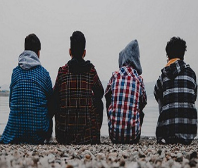 Cuatro jóvenes en riesgo de exclusión social mirando al mar en una playa (Fuente: Fundación Integra)