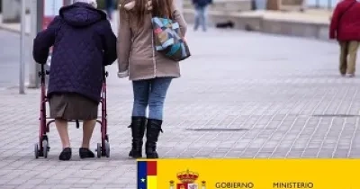 Banner del Ministerio de Derechos Sociales y Agenda 2030 y del Gobierno, junto a una persona dependiente con su acompañante