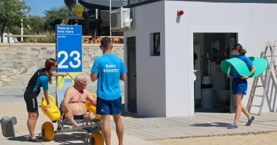 persona mayor dependiente siendo ayudado por personal de ILUNION para acceder en una silla anfibia a la playa