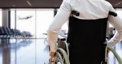 persona en silla de ruedas mirando a un avión que despega al fondo