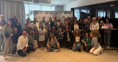Foto de grupo de familias, profesionales y personas con discapacidad reunidas en una sala, posando juntas tras el taller “Adolescencia, familia y discapacidad” de la Fundación Kike Osborne en Valencia, con un photocall de la Fundación al fondo.